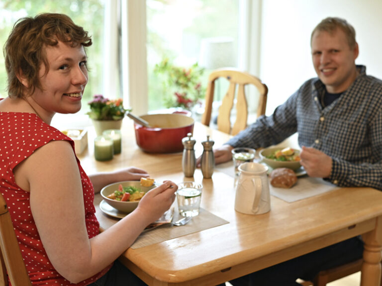 En man och en kvinna sitter vid ett matbord och äter