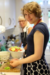 Två kvinnor står vid en köksbänk och gör sallad.